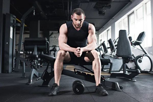 Deportista sentado en el gimnasio mirando la cámara — Foto de Stock