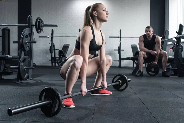 Mujer haciendo entrenamiento de fuerza mientras hombre sentado — Foto de Stock