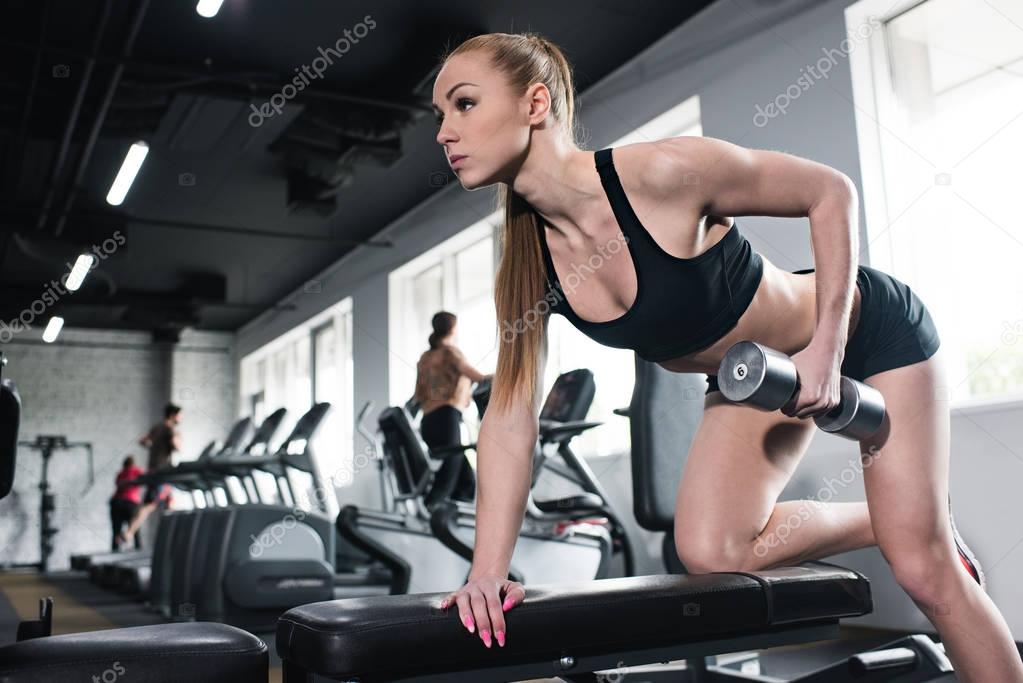 young woman training with dumbbell at gym