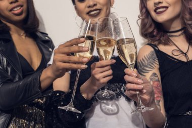 multiethnic girls clinking with glasses of champagne clipart