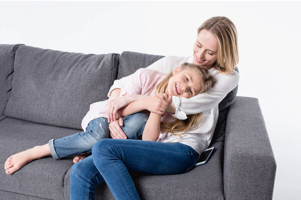 mother with little daughter sitting on sofa