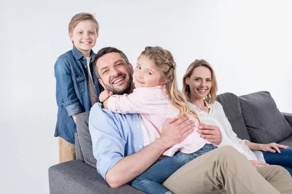 Семья смотрит на камеру, сидя на диване — стоковое фото