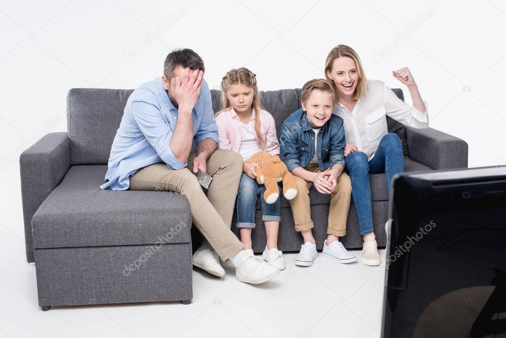 family sitting on sofa and watching tv