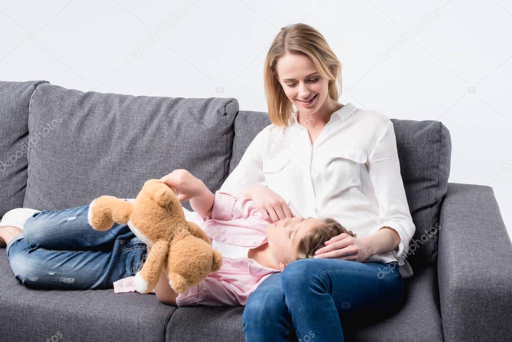 mother with little daughter sitting on sofa