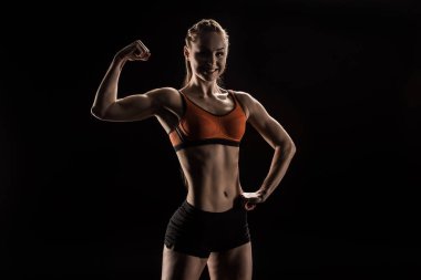 young smiling sportswoman flexing biceps clipart