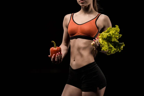 Sportswoman holding bell pepper and lettuce — Stock Photo, Image