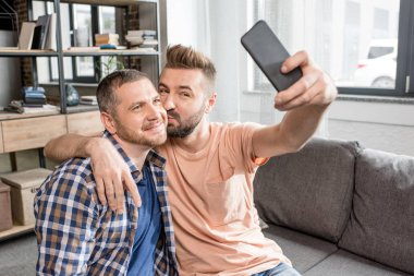 homosexual couple taking selfie on smartphone clipart