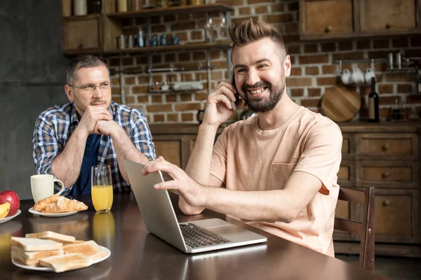 Homem usando laptop durante o café da manhã — Fotografia de Stock