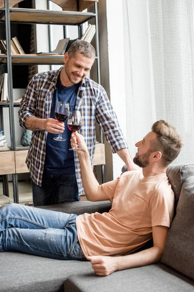 Homosexual couple clinking with glasses of wine — Free Stock Photo