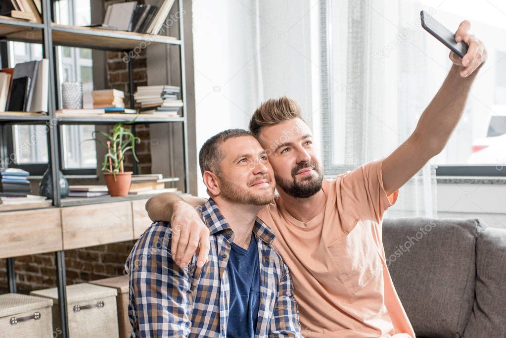 homosexual couple taking selfie on smartphone