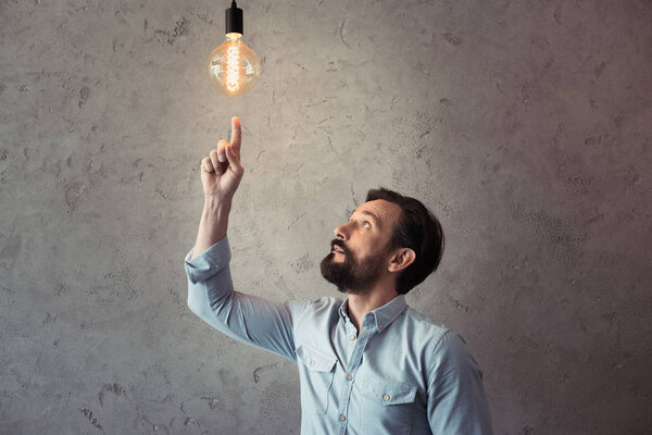 man pointing at illuminated light bulb