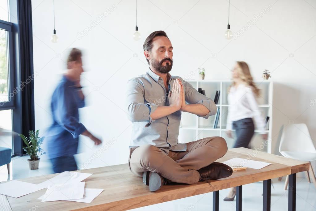 Businessman meditating in office 