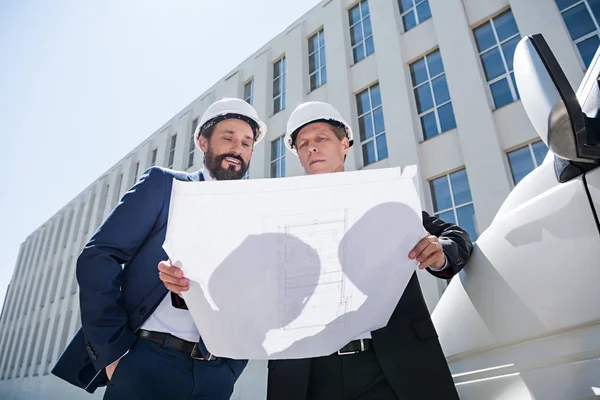 Bauunternehmer schauen sich Bauplan im stehenden Bus an — Stockfoto