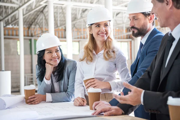 planları ile çalışan takım elbiseli çok ırklı mimarlar