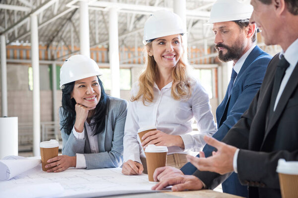 multiethnic architects in suits working with blueprints