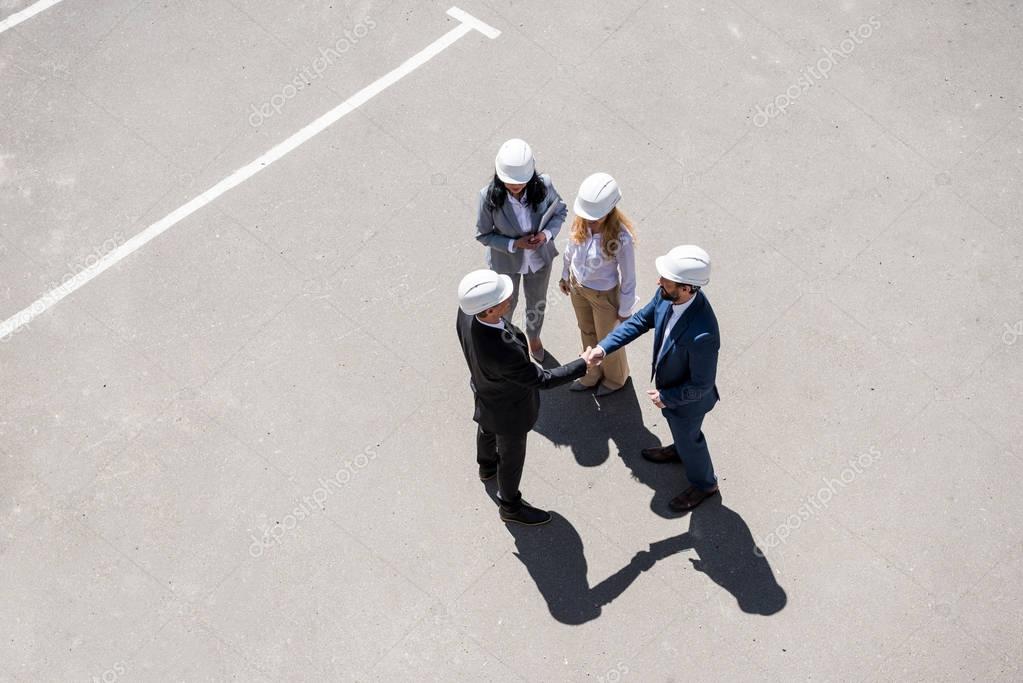 Aerial view of group of architects in formal wear talking at meeting outdoors