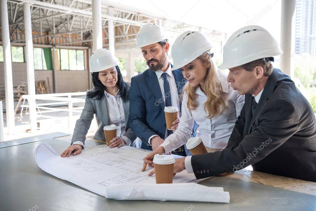 contractors in formal wear working with blueprints