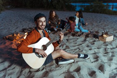 musician playing guitar on sandy beach clipart