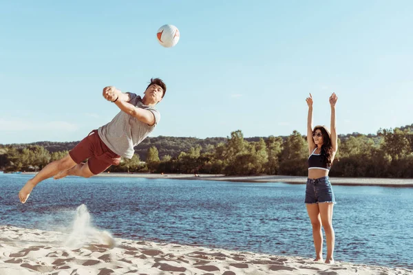 Друзья играют в волейбол на песчаном пляже — стоковое фото