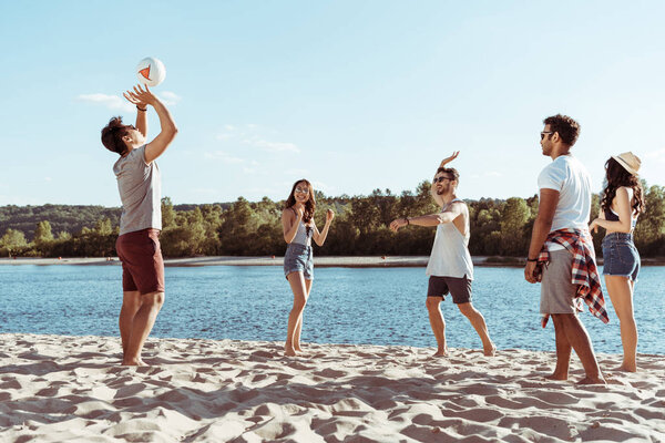friends playing volleyball on sandy beach
