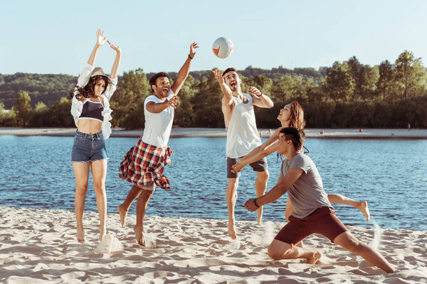 друзья играют в пляжный волейбол на берегу реки
