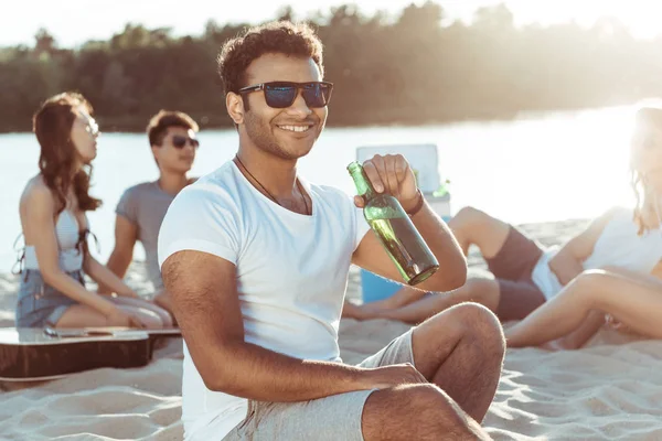 Young man drinking beer on beach — Stock Photo, Image