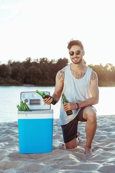 Uomo che prende birra dal frigorifero portatile — Foto Stock