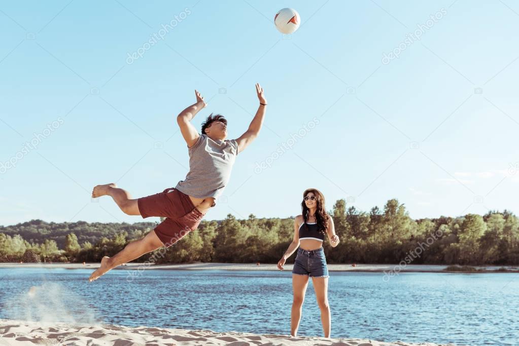friends playing volleyball on sandy beach