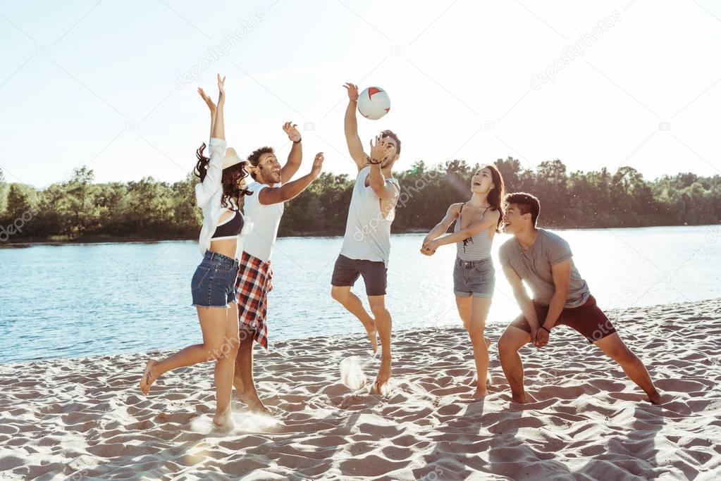 friends playing volleyball on sandy beach