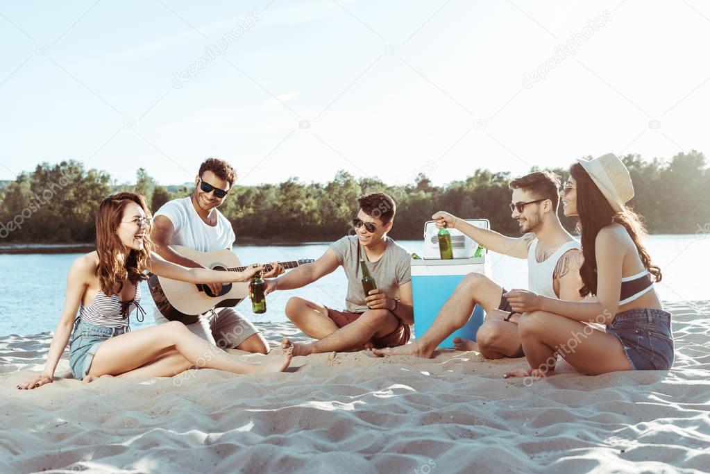 happy young friends resting on beach