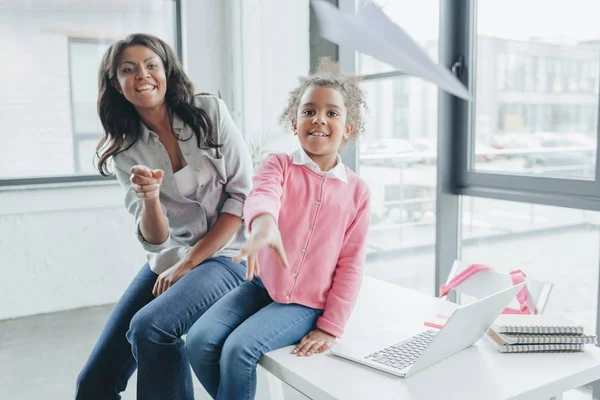 Daughter with mother throwing paper airplane — Stock Photo, Image