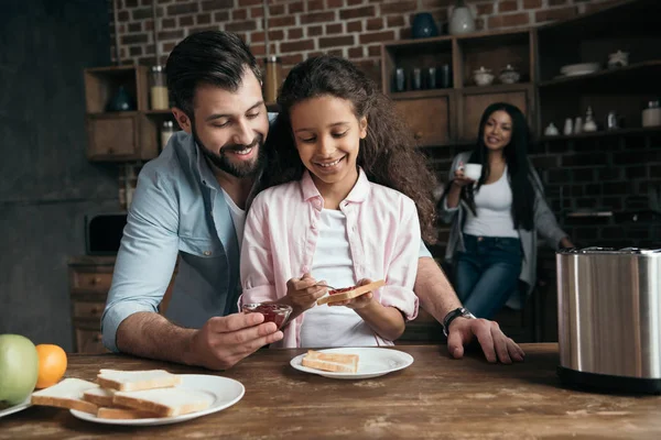 Pai e filha preparando torradas com geléia — Fotografia de Stock