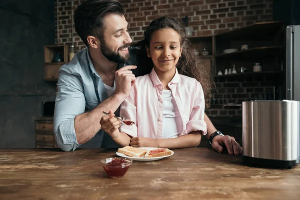 Father and daughter preparing toasts with jam — Stock Photo, Image