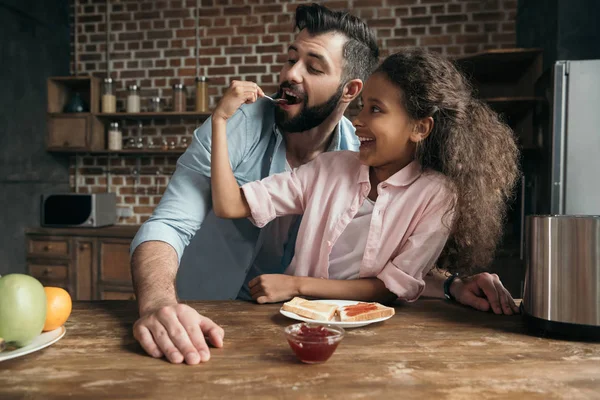 Girl feeding father with jam — Stock Photo, Image