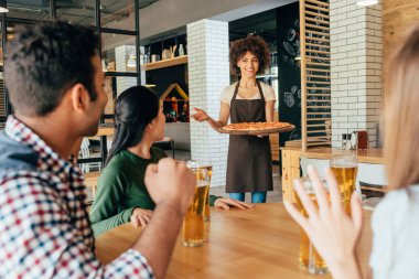 waitress bringing pizza for clients clipart