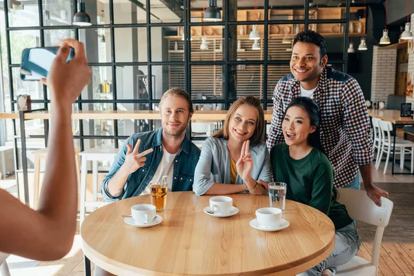 Woman taking photo of friends at cafe — Free Stock Photo