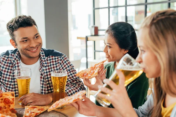 Amigos comiendo pizza con cerveza en la cafetería —  Fotos de Stock