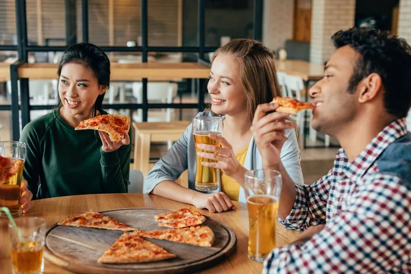 Amici che mangiano pizza con birra nel caffè — Foto Stock