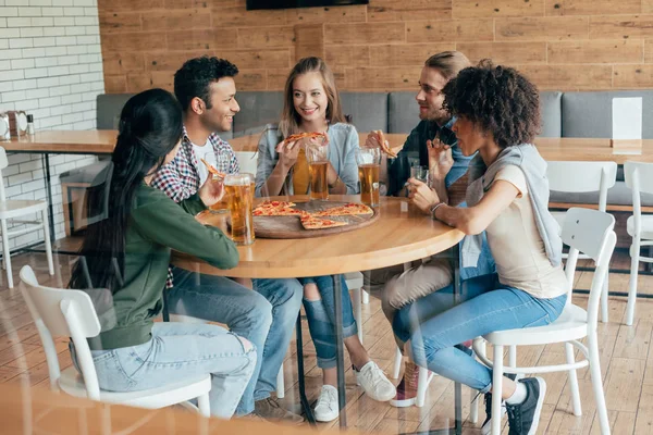 Friends eating pizza with beer in cafe — Stock Photo, Image