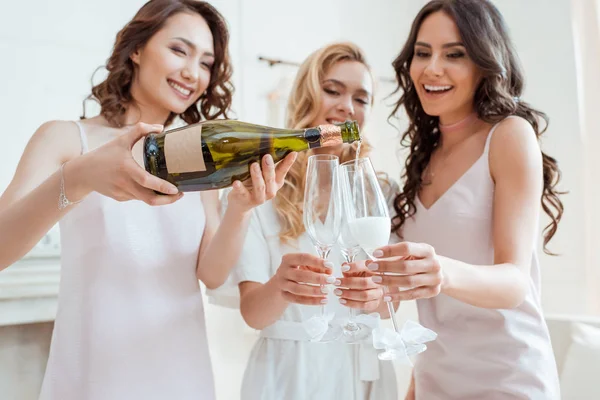 Bruid met de bruidsmeisjes gieten van champagne in glazen — Stockfoto