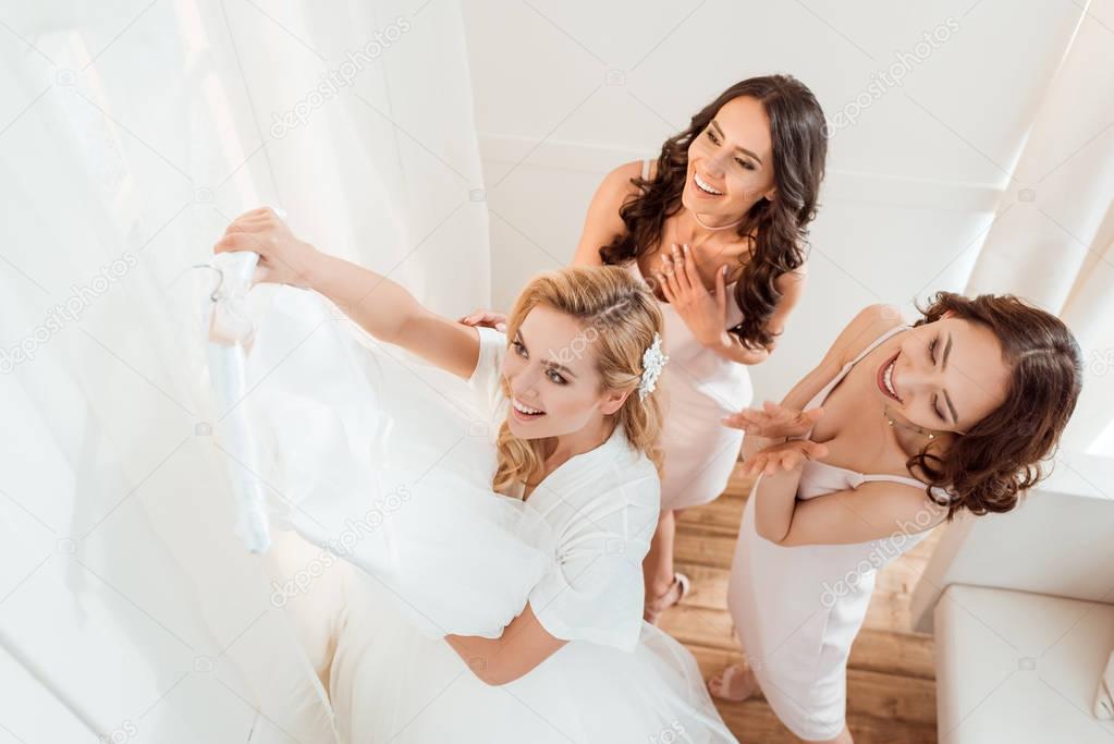bride with bridesmaids looking at wedding dress