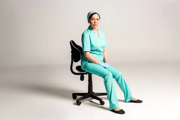 Azjatycki lekarz siedzi na krześle — Zdjęcie stockowe