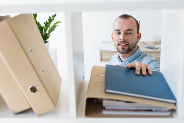 businessman reaching for paperwork on shelf