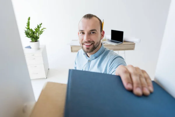 Businessman reaching for paperwork on shelf — Stock Photo, Image