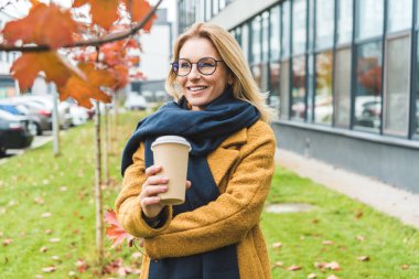 attractive woman with coffee in autumn park clipart
