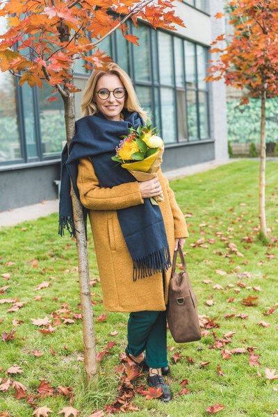 stylish woman with flowers in autumn park