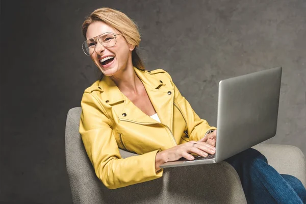 Жінка сміється, використовуючи ноутбук — стокове фото