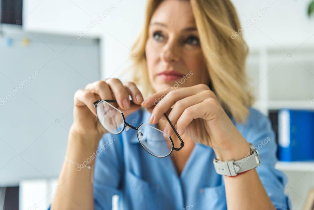 woman holding eyeglasses