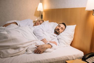 otel odasında yatakta yatmaya bornoz güzel orta yaşlı çift 