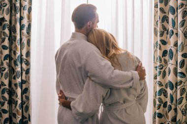 arkadan görünüşü bornoz giyiyor ve otel odasında sarılma aşık Olgun çift 